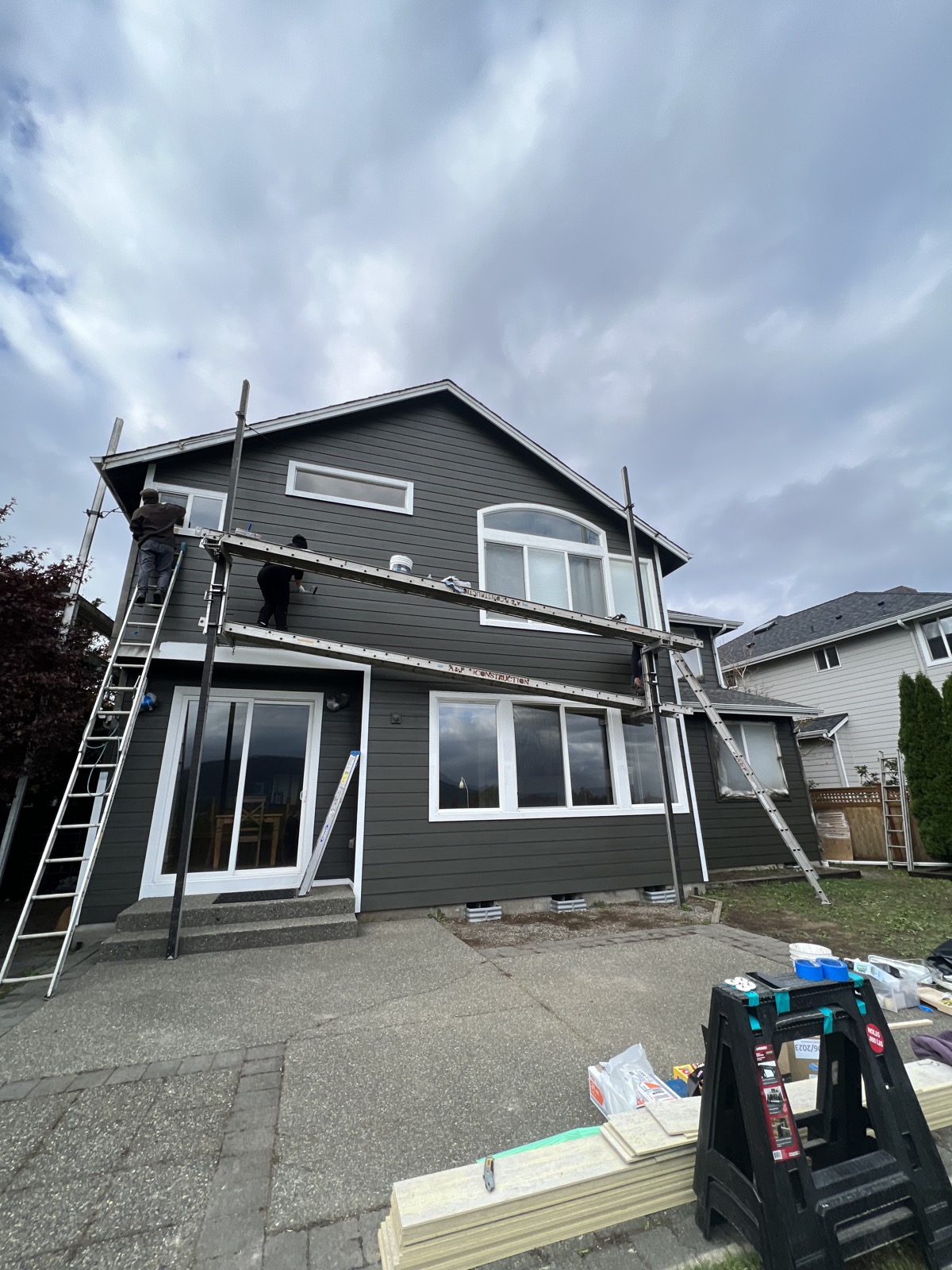 Charcoal board-and-batten siding re-side in progress with crew on scaffolding, Tacoma